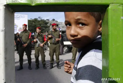 A Palestinian boy looks on as members Palestinian security forces take part in a rally in solidarity with al-Aqsa mosque in Jerusalem, in Rafah in the southern Gaza Strip, December 11, 2014. Photo by Abed Rahim Khatib