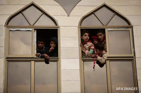 Palestinian youth look on as Hamas supporters take part in a rally ahead of the 27th anniversary of the movement founding, in Jabaliya in the northern Gaza Strip December 12, 2014. Photo by Ashraf Amra