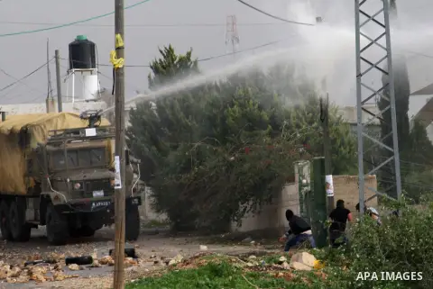 Palestinian protesters take cover from foul smelling water sprayed by an Israeli military vehicle during clashes against the expropriation of Palestinian land by Israel following Friday prayers in the village of Kafr Qad...