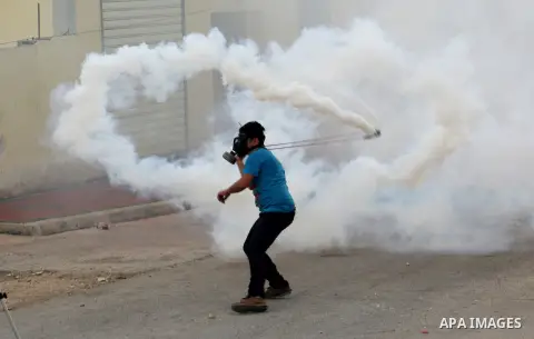 A Palestinian protester throws back a tear gas canister using a slingshot at Israeli security forces during clashes in a protest against the expropriation of Palestinian land by Israel following Friday prayers in the vil...