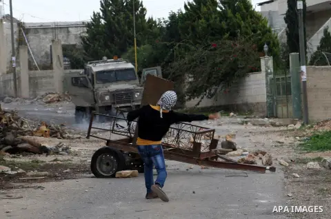 Palestinian youths throw stones at Israeli security forces during clashes in a protest against the expropriation of Palestinian land by Israel following Friday prayers in the village of Kafr Qaddum, near Nablus, Dec. 12,...