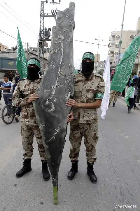 Palestinian militants from the Ezzedine al-Qassam brigade take part during a rally to commemorate the 27th anniversary of the Islamist movement s creation, at the Nuseirat refugee camp in the Central Gaza Strip on Decemb...
