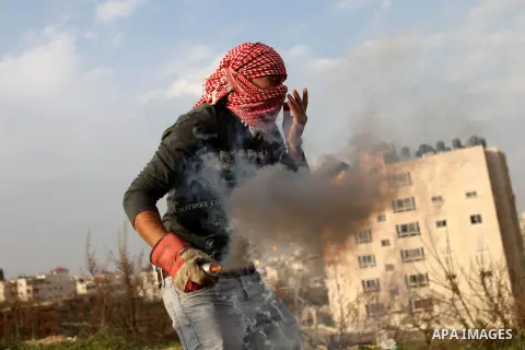 A Palestinian protester uses a slingshot to throw stones at Israeli troops during clashes near Israel's Ofer Prison, near the West Bank city of Ramallah December 12, 2014. Photo by Shadi Hatem