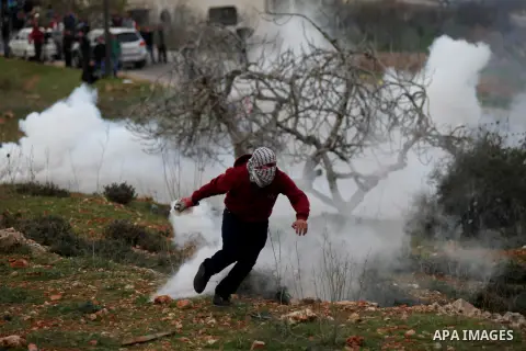 A Palestinian protester uses a slingshot to throw stones at Israeli troops during clashes near Israel's Ofer Prison, near the West Bank city of Ramallah December 12, 2014. Photo by Shadi Hatem