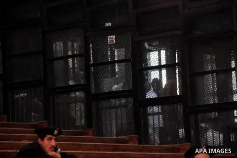 Egyptian Muslim Brotherhood members stand inside the defendants cage during their trial in the capital Cairo on December 13, 2014. Resumption of trial of Muslim Brotherhood Supreme Guide Mohamed Badie and 50 others in th...