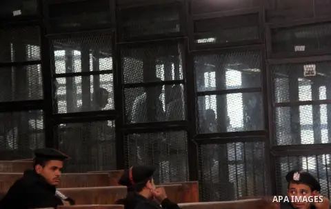 Egyptian Muslim Brotherhood members stand inside the defendants cage during their trial in the capital Cairo on December 13, 2014. Resumption of trial of Muslim Brotherhood Supreme Guide Mohamed Badie and 50 others in th...