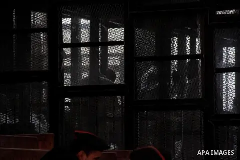 Egyptian Muslim Brotherhood members stand inside the defendants cage during their trial in the capital Cairo on December 13, 2014. Resumption of trial of Muslim Brotherhood Supreme Guide Mohamed Badie and 50 others in th...