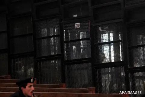 Egyptian Muslim Brotherhood members stand inside the defendants cage during their trial in the capital Cairo on December 13, 2014. Resumption of trial of Muslim Brotherhood Supreme Guide Mohamed Badie and 50 others in th...
