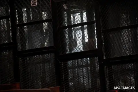 Egyptian Muslim Brotherhood members stand inside the defendants cage during their trial in the capital Cairo on December 13, 2014. Resumption of trial of Muslim Brotherhood Supreme Guide Mohamed Badie and 50 others in th...