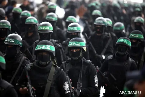 Palestinian members of al-Qassam Brigades, the armed wing of the Hamas movement, hold weapons as they take part in a military parade marking the 27th anniversary of Hamas' founding, in Gaza City December 14, 2014. Photo...