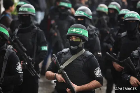 Palestinian members of al-Qassam Brigades, the armed wing of the Hamas movement, hold weapons as they take part in a military parade marking the 27th anniversary of Hamas' founding, in Gaza City December 14, 2014. Photo...