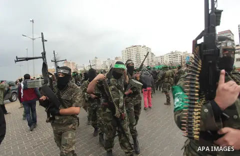 Palestinian members of al-Qassam Brigades, the armed wing of the Hamas movement, hold weapons as they take part in a military parade marking the 27th anniversary of Hamas' founding, in Gaza City December 14, 2014. Photo...