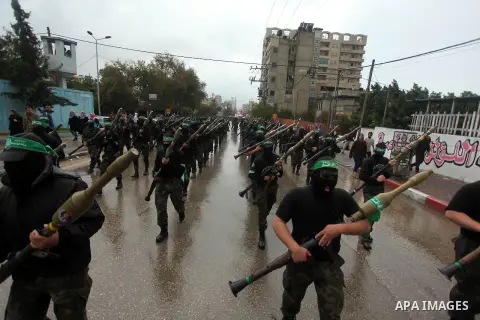 Palestinian members of al-Qassam Brigades, the armed wing of the Hamas movement, hold weapons as they take part in a military parade marking the 27th anniversary of Hamas' founding, in Gaza City December 14, 2014. Photo...