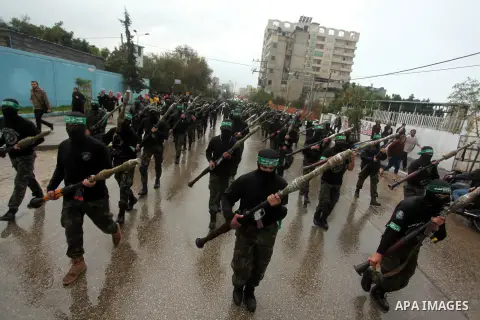 Palestinian members of al-Qassam Brigades, the armed wing of the Hamas movement, hold weapons as they take part in a military parade marking the 27th anniversary of Hamas' founding, in Gaza City December 14, 2014. Photo...