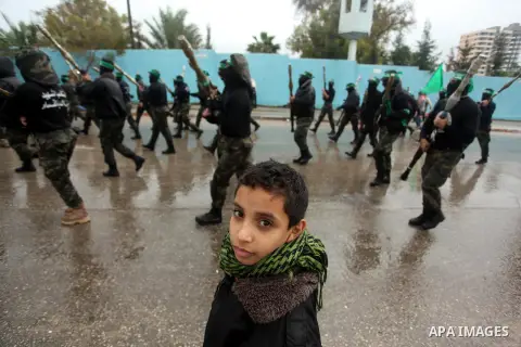 Palestinian members of al-Qassam Brigades, the armed wing of the Hamas movement, hold weapons as they take part in a military parade marking the 27th anniversary of Hamas' founding, in Gaza City December 14, 2014. Photo...