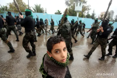 Palestinian members of al-Qassam Brigades, the armed wing of the Hamas movement, hold weapons as they take part in a military parade marking the 27th anniversary of Hamas' founding, in Gaza City December 14, 2014. Photo...