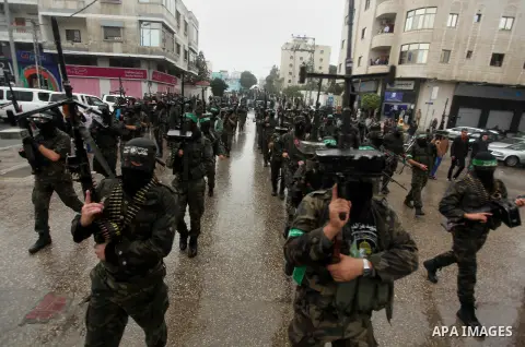 Palestinian members of al-Qassam Brigades, the armed wing of the Hamas movement, hold weapons as they take part in a military parade marking the 27th anniversary of Hamas' founding, in Gaza City December 14, 2014. Photo...