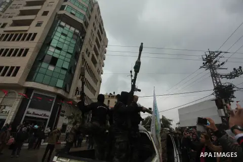 Palestinian members of al-Qassam Brigades, the armed wing of the Hamas movement, hold weapons as they take part in a military parade marking the 27th anniversary of Hamas' founding, in Gaza City December 14, 2014. Photo...