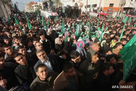 People watch as Palestinian members of al-Qassam Brigades, the armed wing of the Hamas movement, take part in a military parade marking the 27th anniversary of Hamas' founding, in Gaza City December 14, 2014. Photo by As...