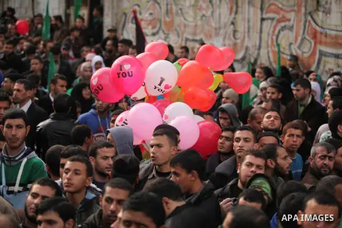 People watch as Palestinian members of al-Qassam Brigades, the armed wing of the Hamas movement, take part in a military parade marking the 27th anniversary of Hamas' founding, in Gaza City December 14, 2014. Photo by As...