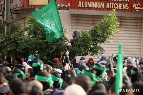 People watch as Palestinian members of al-Qassam Brigades, the armed wing of the Hamas movement, take part in a military parade marking the 27th anniversary of Hamas' founding, in Gaza City December 14, 2014. Photo by As...