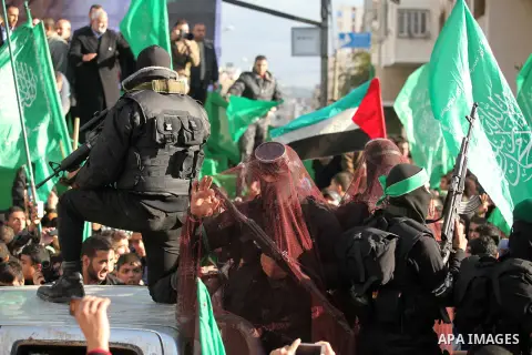 Palestinian members of al-Qassam Brigades, the armed wing of the Hamas movement, hold weapons as they take part in a military parade marking the 27th anniversary of Hamas' founding, in Gaza City December 14, 2014. Photo...