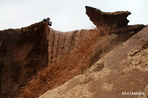 A Palestinian man takes a picture while rains water falling from a cliff in the Jordan Valley near West Bank city of Jericho on December 14, 2014. Israel has heavily invested in transferring the Jordan Valley into a comp...