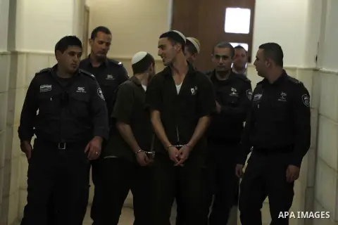 Three Israeli suspects, members of the right-wing Lehava organisation, are escorted by security to a hearing at the District Court in Jerusalem on December 15, 2014. The three are suspects behind an arson attack last mon...