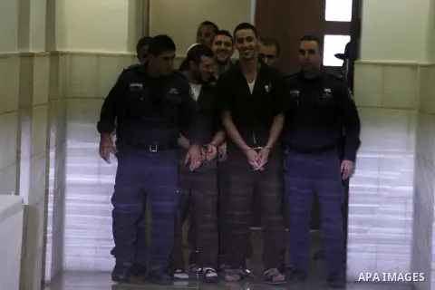 Three Israeli suspects, members of the right-wing Lehava organisation, are escorted by security to a hearing at the District Court in Jerusalem on December 15, 2014. The three are suspects behind an arson attack last mon...