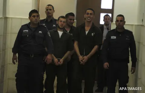 Three Israeli suspects, members of the right-wing Lehava organisation, are escorted by security to a hearing at the District Court in Jerusalem on December 15, 2014. The three are suspects behind an arson attack last mon...