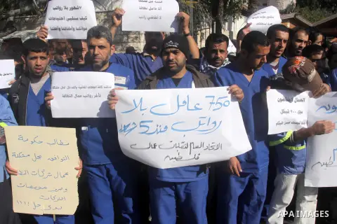 Palestinian cleaners hold banners during a protest to demand their salaries, in Gaza City December 16, 2014. Photo by Mohammed Asad