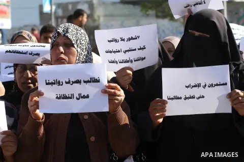Palestinian cleaners hold banners during a protest to demand their salaries, in Gaza City December 16, 2014. Photo by Mohammed Asad