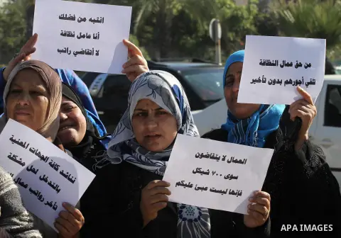 Palestinian cleaners hold banners during a protest to demand their salaries, in Gaza City December 16, 2014. Photo by Mohammed Asad