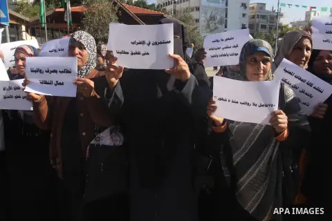 Palestinian cleaners hold banners during a protest to demand their salaries, in Gaza City December 16, 2014. Photo by Mohammed Asad