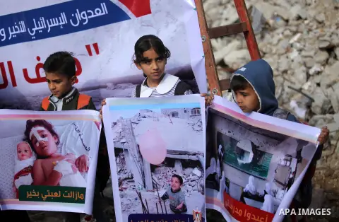 Palestinian children hold banners during a media conference organised by the ministry of women affairs in front of the Italian Complex, which was destroyed by Israeli air strike during the Israel-Gaza conflict, in Gaza c...