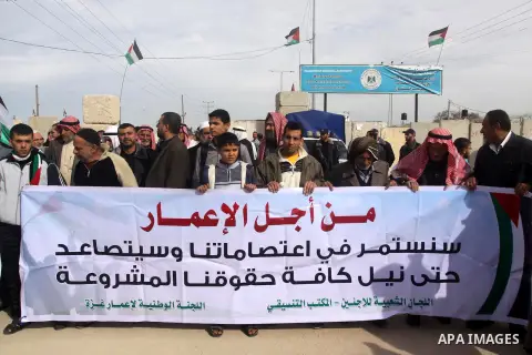Palestinians gather during a protest against the delay in acquiring building material in front of Eriz crossing border, in the norhtern Gaza Strip on December 18, 2014. According to housing minister Mufeed al-Hasayna, Ga...