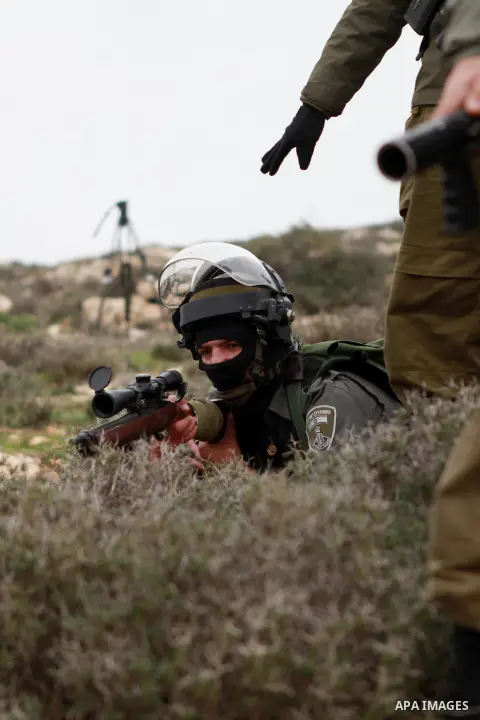 An Israeli soldier aims his weapon during clashes with activists and Palestinian protesters following a demonstration against Israeli settlements in the West Bank village of Turmus Aya, near Ramallah December 19, 2014. P...