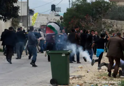 Palestinians run for cover from a tear gas during clashes against the expropriation of Palestinian land by Israel following Friday prayers in the village of Kafr Qaddum, near Nablus, Dec. 19, 2014. Photo by Nedal Eshtaya...