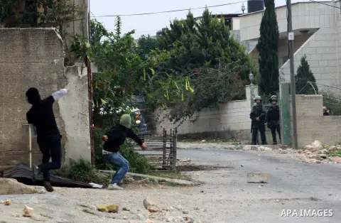 Palestinian youths throw stones at Israeli security forces during clashes in a protest against the expropriation of Palestinian land by Israel following Friday prayers in the village of Kafr Qaddum, near Nablus, Dec. 19,...