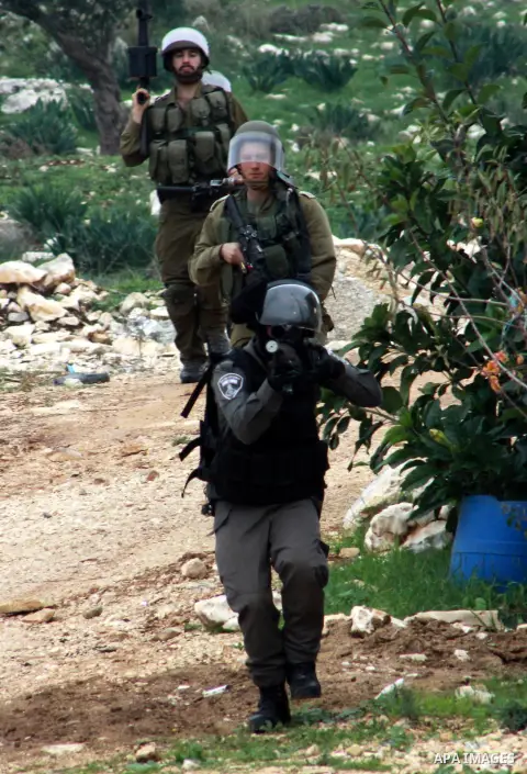 A member of Israeli security forces aims his gun at Palestinian protesters during clashes in a protest against the expropriation of Palestinian land by Israel following Friday prayers in the village of Kafr Qaddum, near...