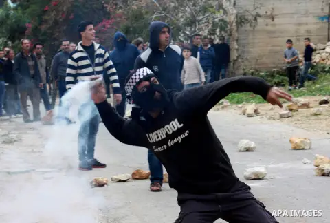 A Palestinian protester throws back a tear gas canister at Israeli security forces during clashes in a protest against the expropriation of Palestinian land by Israel following Friday prayers in the village of Kafr Qaddu...