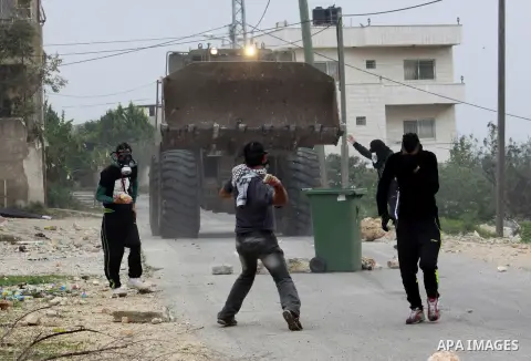 Palestinian youths throw stones at Israeli security forces during clashes in a protest against the expropriation of Palestinian land by Israel following Friday prayers in the village of Kafr Qaddum, near Nablus, Dec. 19,...