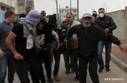 Palestinians carry a wounded fellow during clashes against the expropriation of Palestinian land by Israel following Friday prayers in the village of Kafr Qaddum, near Nablus, Dec. 19, 2014. Photo by Nedal Eshtayah