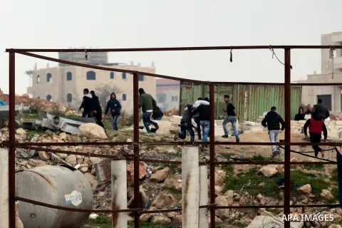 Palestinian protesters throw stones at Israeli security forces during clashes following a demonstration against Israeli settlements at Qalandiya checkpoint near the West Bank City of Ramallah on December 19, 2014. A Pale...