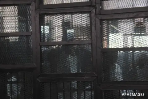 Political activist Alaa Abdel Fattah with 24 others, stand inside the defendants cage during their trial, in Cairo, Egypt, on December 20, 2014. The court postponed to December 27 the verdict in the trial of the Events E...