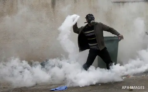 A Palestinian protestor throws back a tear gas canister towards member of the Israeli security forces during clashes following a demonstration against the expropriation of Palestinian land by Israel in the West Bank vill...