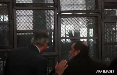 Egyptian suspects of the Muslim Brotherhood movement leaders stand behind a court room during their trial in Cairo on January 5, 2014. Cairo criminal court adjourned, today, Monday, the trial of supreme leader of Muslim...