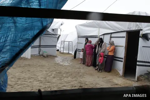 Palestinians, whose houses were destroyed by what they said was Israeli shelling during a 50- day-war last summer, stand outside containers used as temporary replacement for their damaged homes, on a stormy day in the ea...