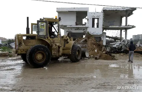 Palestinians, whose houses were destroyed by what they said was Israeli shelling during a 50- day-war last summer, use a bulldozer to remove rubbles on a stormy day in the east of Khan Younis in the southern Gaza Strip J...