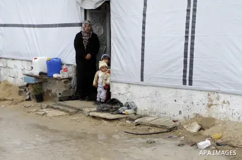 A Palestinian woman, who lives in a container as a temporary replacement for her house which was destroyed by what she said was Israeli shelling during a 50- day-war last summer, stands outside a container on a stormy da...